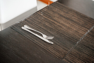 A black table adorned with a polished fork and knife, patiently awaits the arrival of a sumptuous...