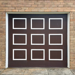 mid century old dark brown garage door with white wooden square frames against brick wall on house
