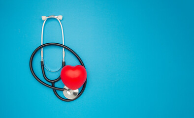 Cardiology specialist. Top view of a stethoscope and a red heart shape on a blue background.