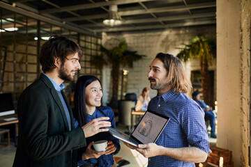 Colleagues collaborating on a project with laptop in a casual office environment