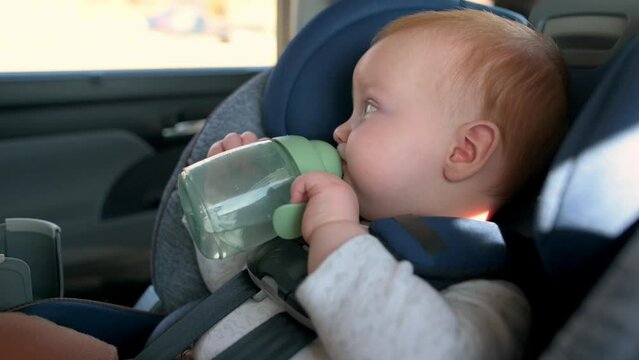 a child securely seated in a car seat. drink water.  Capture the joy and excitement of travel, the child's wonder at the passing scenery, and the importance of safe travel for families. Ideal for fami