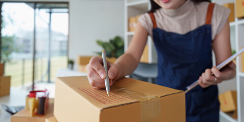 Close up of woman entrepreneur working at home office and checking a parcel before delivery