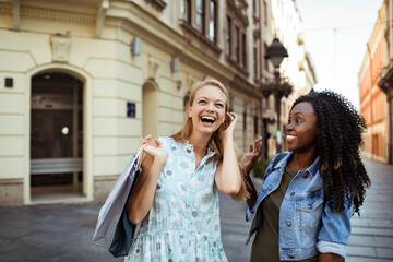 Two friends shopping and laughing together on city street