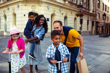 Joyful diverse family having fun on a city walk - obrazy, fototapety, plakaty
