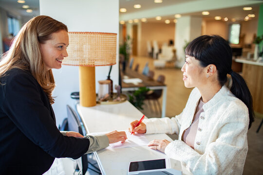 Professional woman signing contract at office reception desk