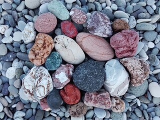 Pile of colorful pebble stones and rocks on sea beach background. Different multicolor pebble...