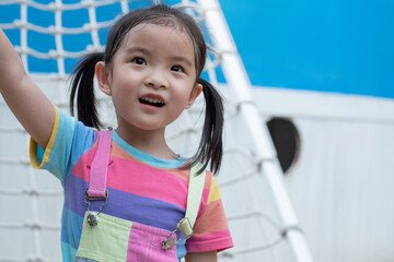 Asian child girl with rope ladder behind her at play ground