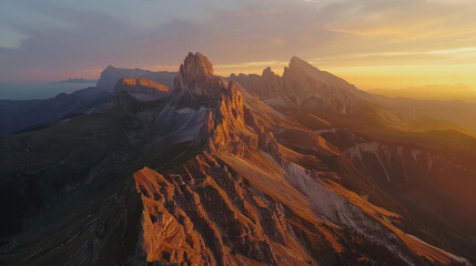 Naklejka premium Aerial view of a mountain range at sunrise, the peaks illuminated with golden light against the shadowed valleys