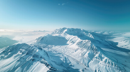 Naklejka premium Aerial view of majestic beauty of a snow-capped mountain range under a clear blue sky