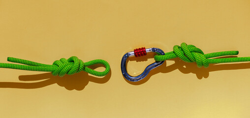 rope with a secure knot and a carabiner lies on a colored background. Equipment for rock climbing and mountaineering. reliable connection. concept of reliability and strength. - 793567170