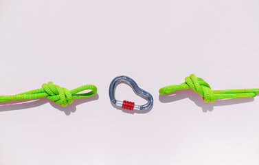 rope with a secure knot and a carabiner lies on a colored background. Equipment for rock climbing and mountaineering. reliable connection. concept of reliability and strength. - 793567534