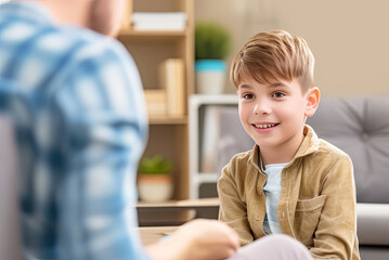 Smiling boy giving card to adult. In background is furniture of playroom. Children and autism. Mental health. Bright colorful photo.