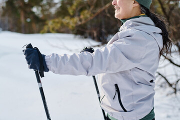 Side view crop shot of cheerful senior woman in sportswear skiing on winter day in park, copy space