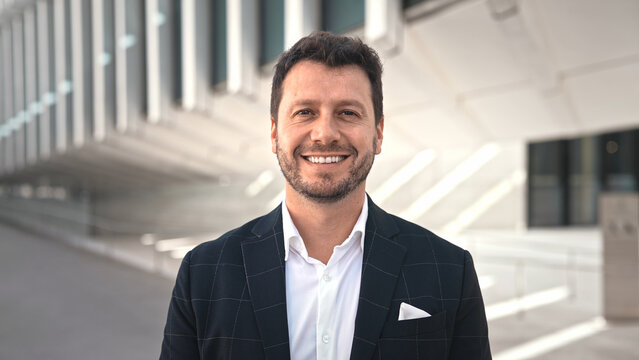 Handsome 30s top manager portrait formal suit. Successful entrepreneur look at camera. Confident business man smile. Young male businessman face. Urban city background. 40s employee work. Office boss.