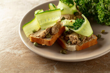 Open sandwiches with pate, cucumber, capers, and parsley.