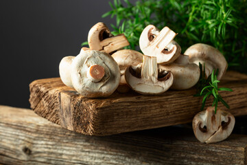 White champignons with rosemary on a wooden board.