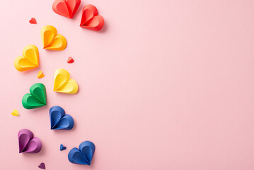 A festive display of multi-colored paper hearts in rainbow hues on a pink surface, symbolically...