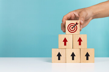 Concept of business success growth increase up, customer target group and planning development. A man arranging wooden block with icon target and arrows pointing up for success