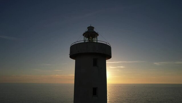 Aerial footage of the Viareggio Tuscany lighthouse taken at sunset with sea and sky behind it