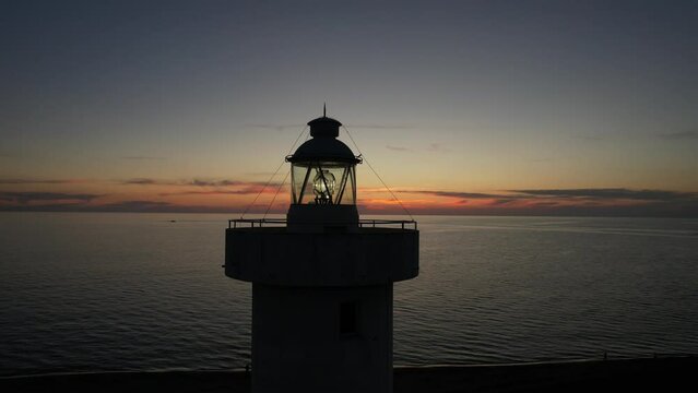 Aerial footage of the Viareggio lighthouse taken at sunset with sea and sky behind it in Tuscany