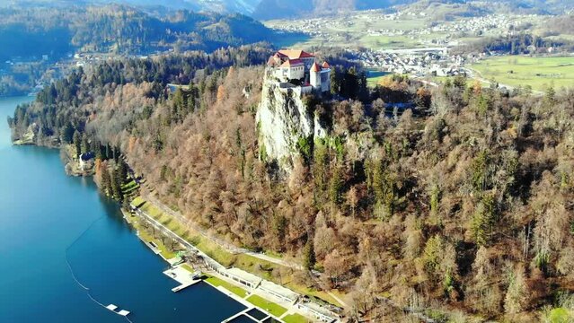 Drone view of Bled Castle surrounded by trees on a hilltop over the Lake Bled in Slovenia
