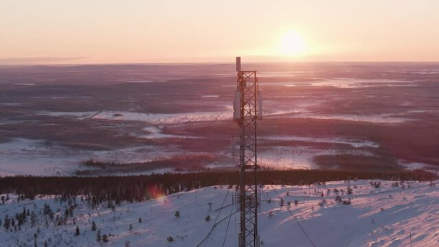Drone flying around a signal tower on snowy mountain at Oy Levi Ski Resort in Finland