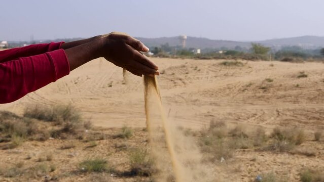 yellow sand slowly releasing from hand at desert at day video is taken at rajasthan, India.