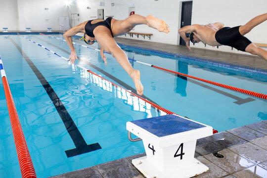 Biracial girl and Caucasian boy dive into pool as swim competitors