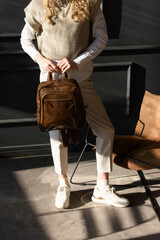 beautiful curly blond hair woman posing with a leather backpack