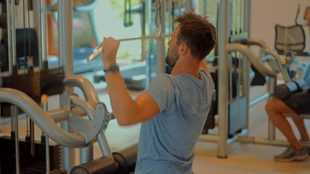 Man lifting weights doing cable pushdown exercises in gym	
