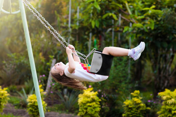 Child swinging on playground. Kids swing. - 793605512