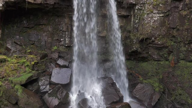 An aerial view of Melinclourt Waterfall on an overcast day, Neath Port Talbot, South Wales. Flying up the face of the fall from bottom to top