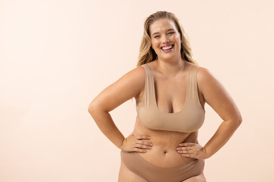 Plus size model with blonde hair and freckles on beige background, copy space