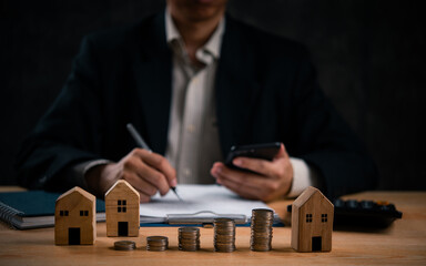 Businessman with coins and house models. Invest house property market or finance banking tax money...