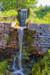 Waterfall by an old mill with a stone wall in the countryside - 793611751