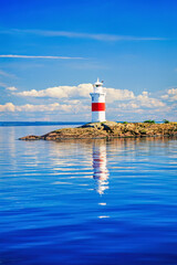 Lighthouse on a skerry with reflections in the water - 793611963