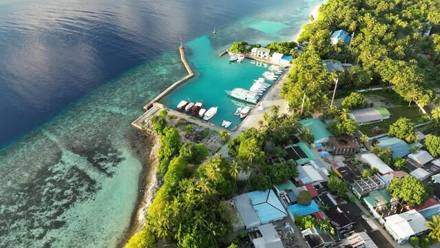 Aerial drone footage flying over the island of Thinadhoo towards the harbour at sunrise.