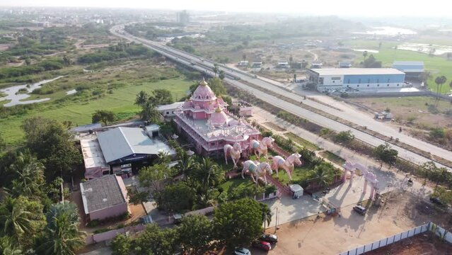 Drone footage of Somaladoddi temple surrounded by trees with a road next to it in India