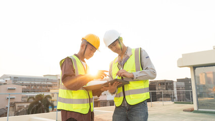 Structural engineer and architect working with blueprints discuss at the outdoors construction site.