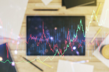 Multi exposure of abstract financial graph and modern digital tablet on desktop on background, top view, financial and trading concept