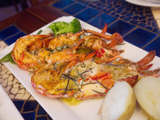 Grilled Lobster halves with potato on the plate on restaurant table 