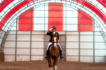 Equestrian rider saluting in indoor red arena