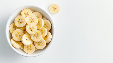 Banana slices in a bowl on a white table top view space on the right