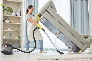 Woman, vacuum and lifting sofa in living room for spring cleaning, hygiene and housekeeping in...