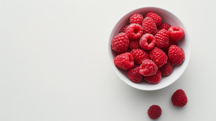 Raspberries in a bowl on a white table top view space on the left