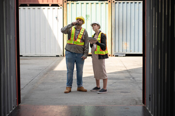 Middle east logistic worker foreman use walkie talkie working with caucasian logistic engineer pregnant woman at container site	