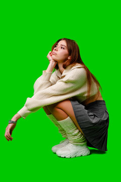 Woman Sitting on Ground in Front of Green Screen