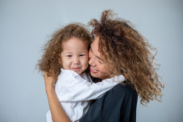 Curly mother and daughter play and laugh on a white background