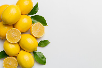 Many fresh ripe lemons with green leaves on colored background, top view, space for text