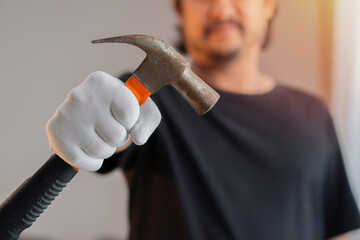 A young man's hand wear white cloth gloves and holding old hammer for home repair work.